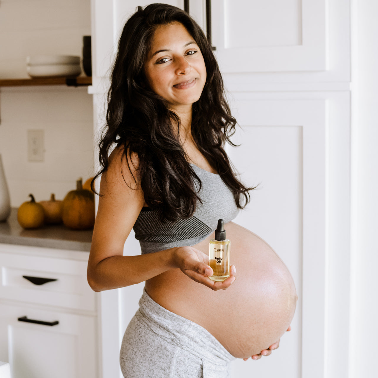 Mama holding Belly Oil from the side showing off her baby bump